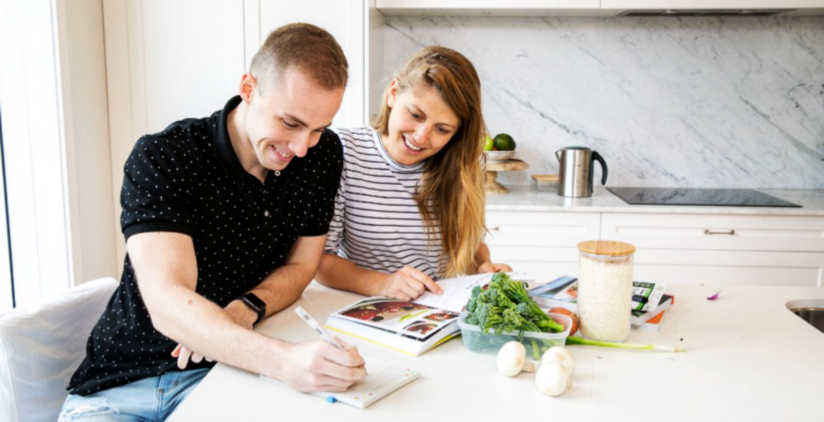 A couple sit at the table writing a shopping list