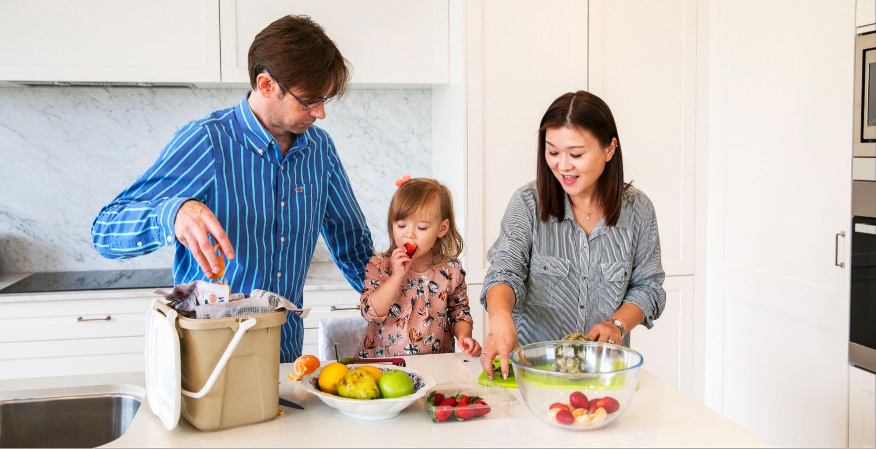 Child with parents cutting up fruit in the kicthen.