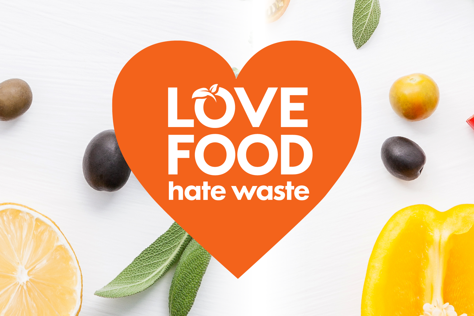 Love Food Hate Waste text in an orange heart with yellow produce in the background