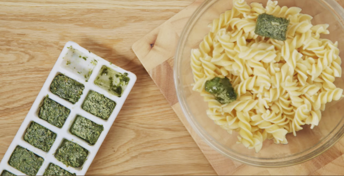 Pesto ice cubes in tray sit next to cooked pasta