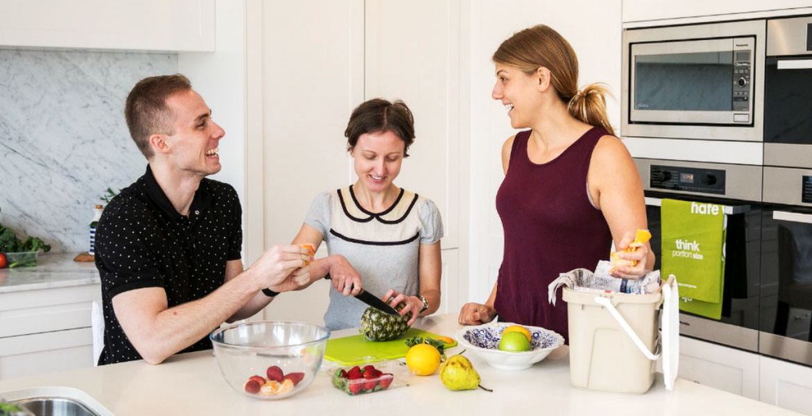 Friends in kitchen laughing and preparing food.