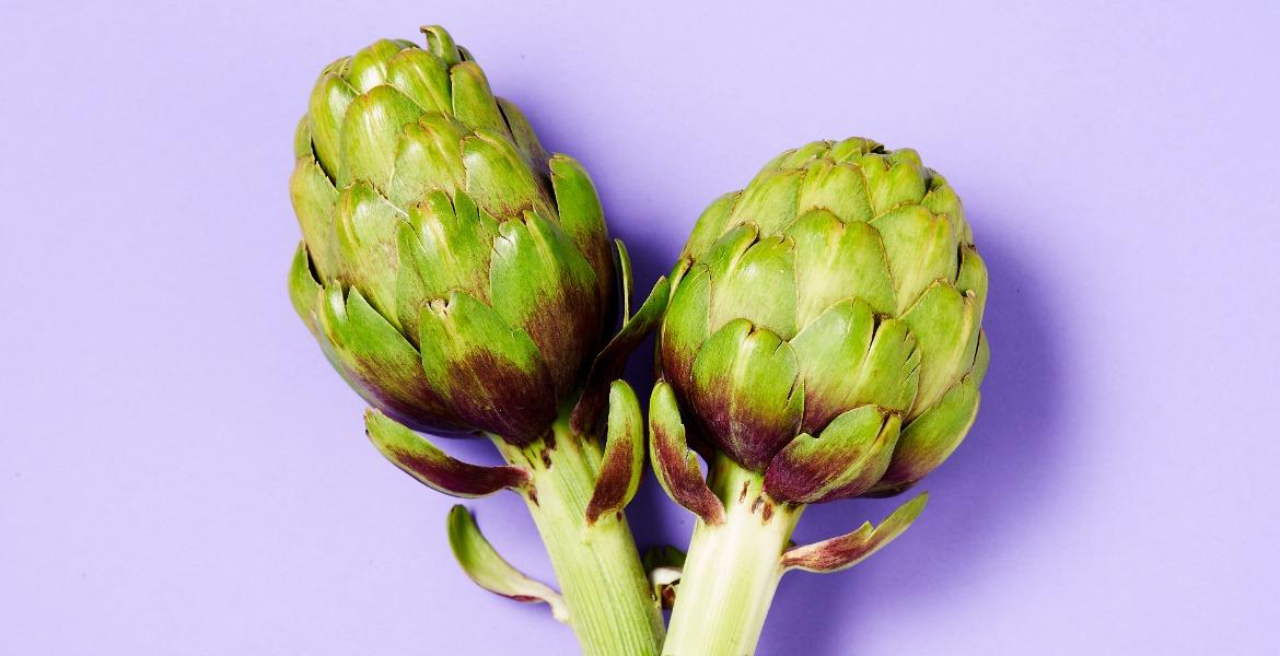 Two artichokes on purple background