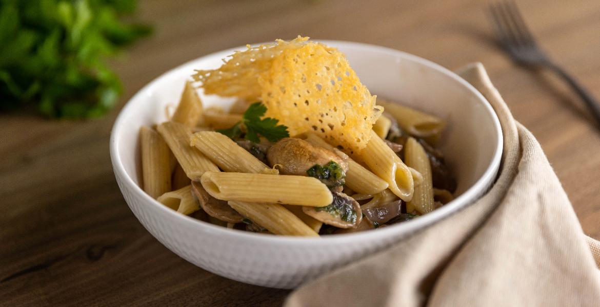 bowl of mushroom penne topped with parmesan crisp