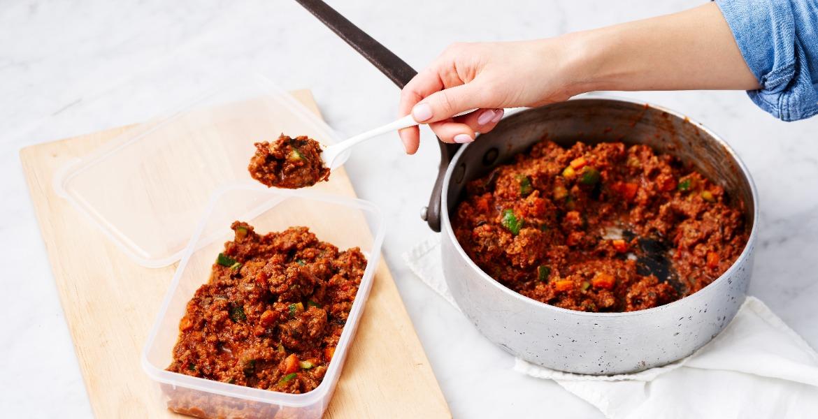 Woman spooning leftover meat into container