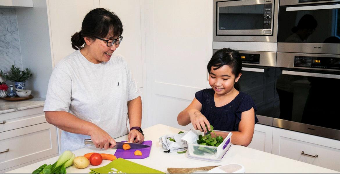 Mother and daughter having fun cutting food in kitchen