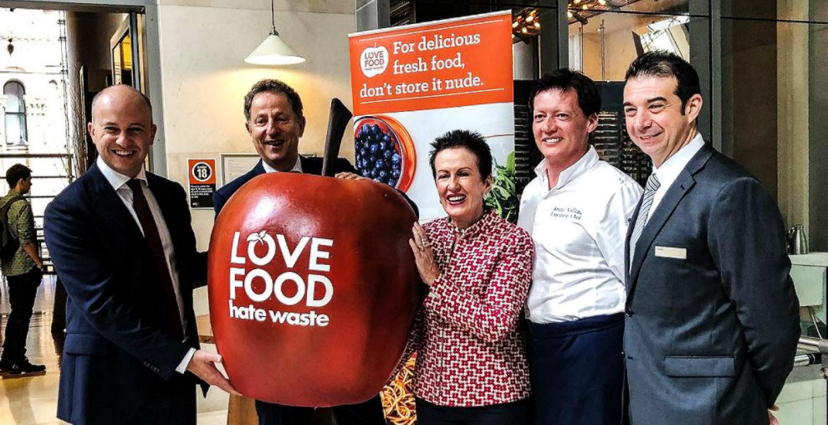 Image of five people holding a giant apple